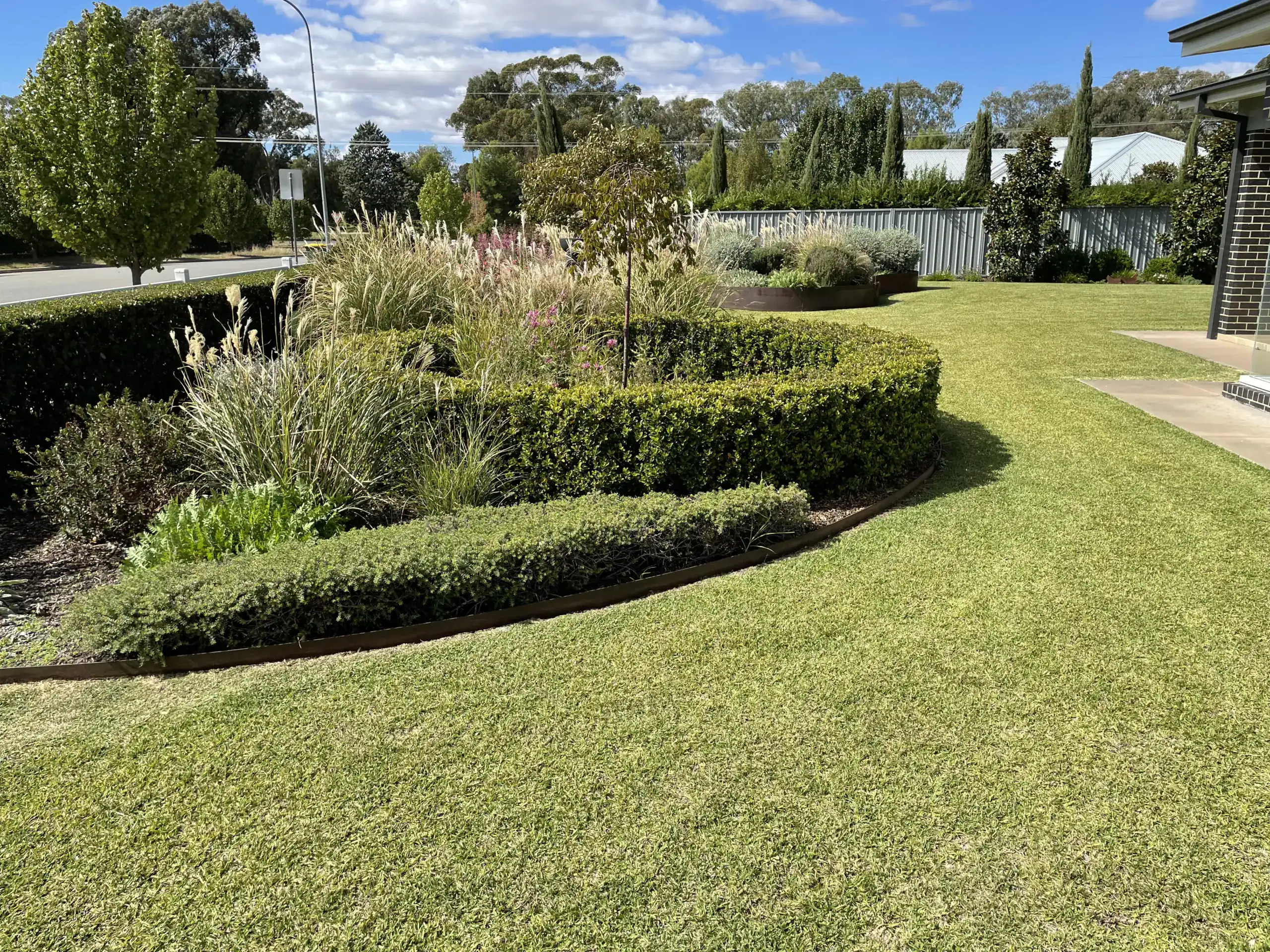 Landscaped suburban front yard with manicured lawn and hedges