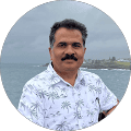 Man with moustache by waterfront wearing patterned shirt