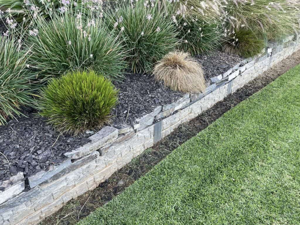 Stone retaining wall with ornamental grasses and lawn